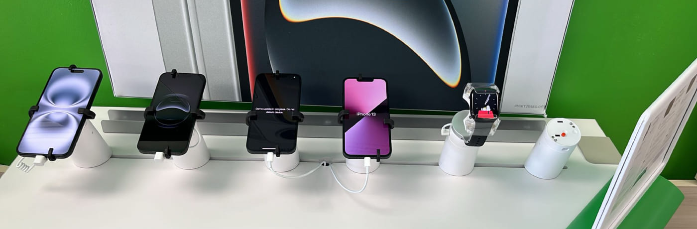 Retail security display stands holding smartphones and a smart watch on a demo table
